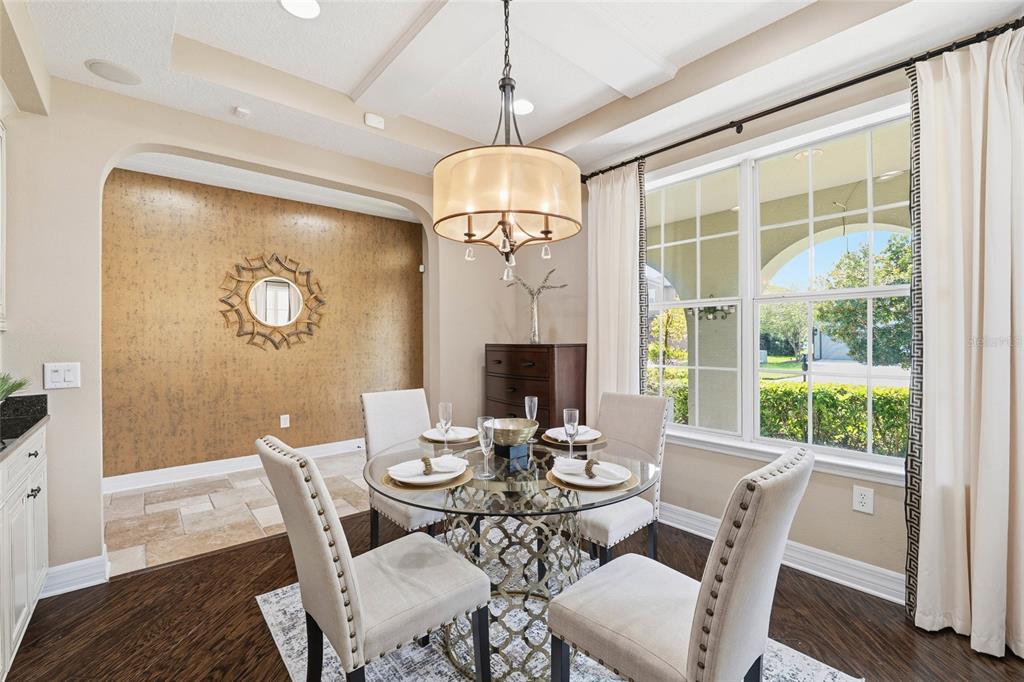 4527 Scarlet Loop Wesley Chapel, FL 33544 - Photo 4 of 57 a dining room with wooden floor a chandelier a glass table and chairs