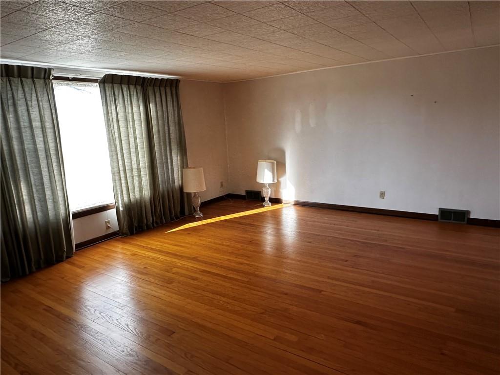 4076 Seneca Road Sharpsville, PA 16150 - Photo 5 of 15 an empty room with wooden floor and windows with curtains