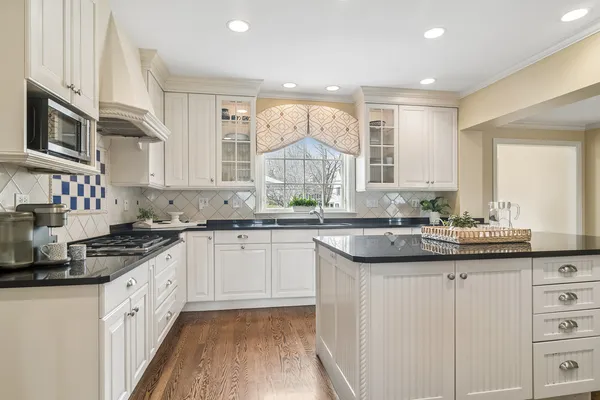 a kitchen with stainless steel appliances granite countertop a table chairs sink and cabinets