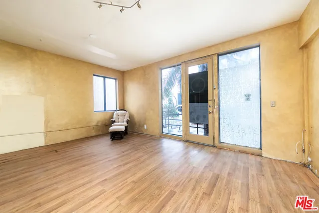 a view of an empty room with window and wooden floor