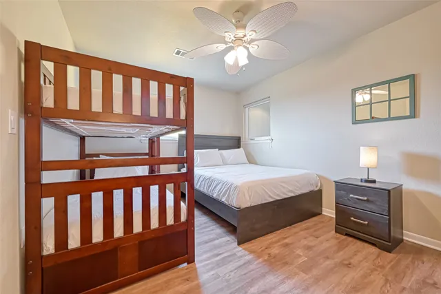 a bedroom with a bed next to a window with wooden floor