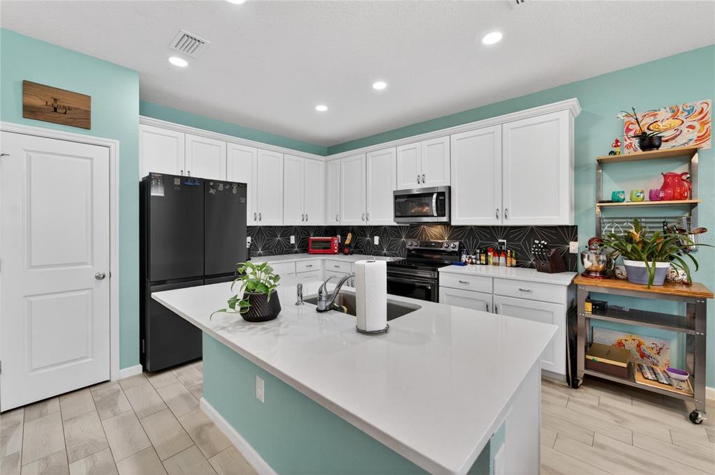 10908 Quickwater Court Riverview, FL 33569 - Photo 11 of 35 a kitchen with stainless steel appliances a refrigerator sink and white cabinets