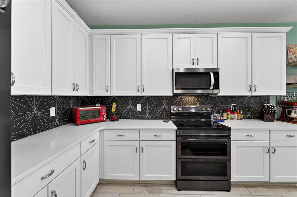 10908 Quickwater Court Riverview, FL 33569 - Photo 13 of 35 a kitchen with white cabinets and black appliances