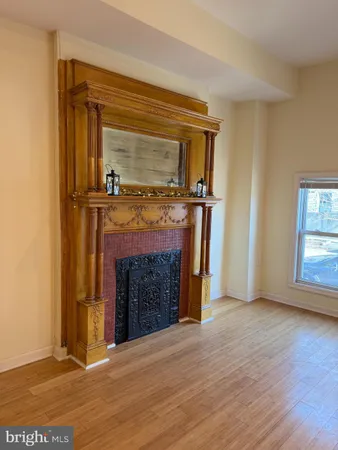 a view of an empty room with wooden floor fireplace and a window