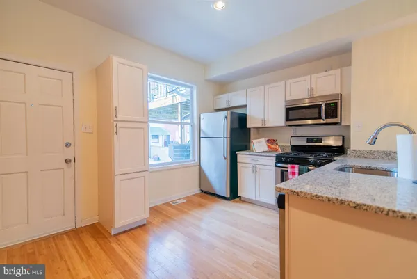 a kitchen with a refrigerator a stove top oven a sink and dishwasher with wooden floor