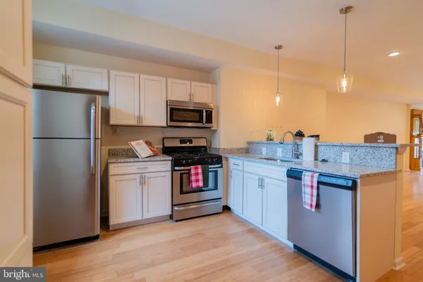 a kitchen with stainless steel appliances granite countertop a refrigerator a stove a sink and a refrigerator