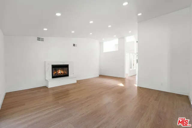 a view of an empty room with wooden floor and a fireplace
