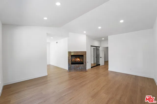 an empty room with wooden floor and fireplace