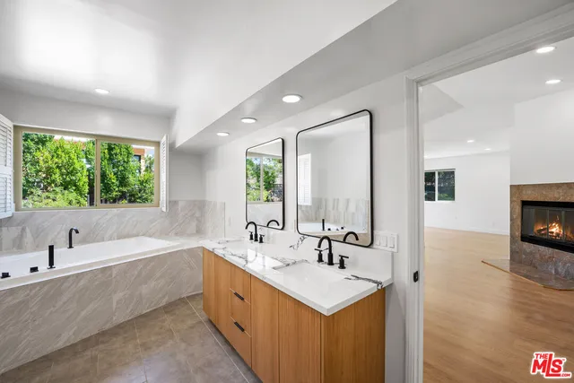 a bathroom with a double vanity sink a mirror and a bathtub