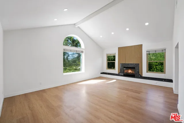 an empty room with windows and fireplace