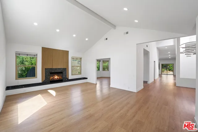 an empty room with wooden floor a fireplace and windows