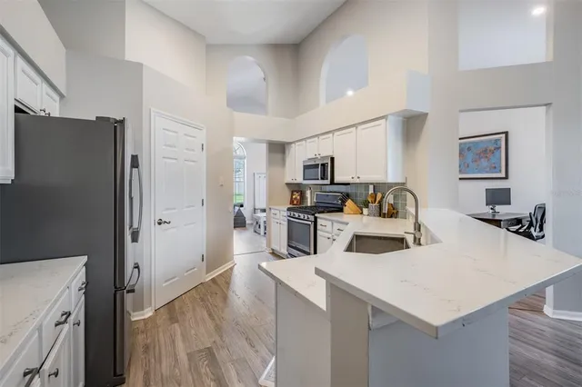 a kitchen with a refrigerator a stove a microwave and white cabinets with wooden floor