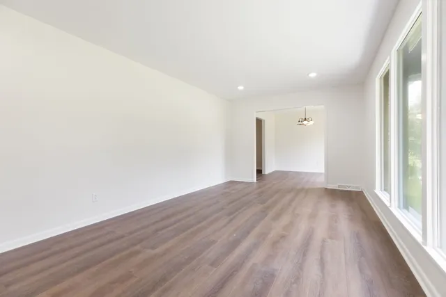 a view of an empty room with a window and wooden floor
