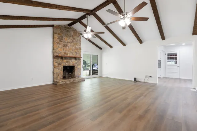 an empty room with wooden floor ceiling fan and windows