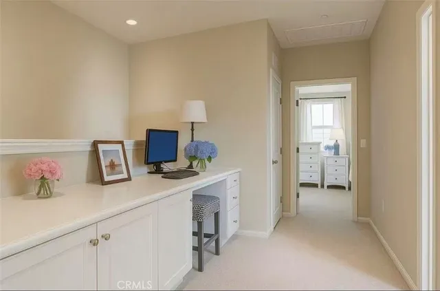 a hallway with a computer on a desk next to a window