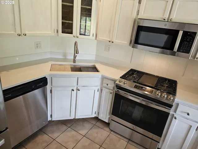 a kitchen with white cabinets and appliances