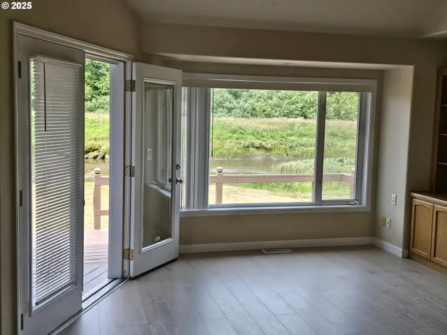 a view of an empty room with wooden floor and a window