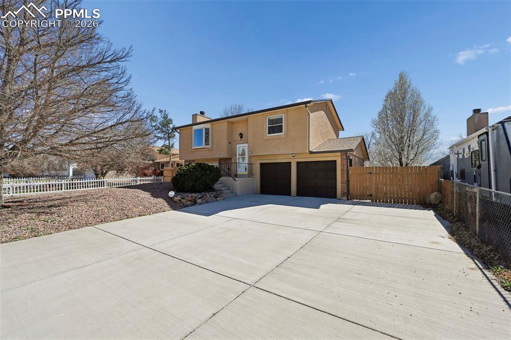 4963 Ridenour Drive Colorado Springs, CO 80916 - Photo 2 of 25 View of front of property with stucco siding, a garage, driveway, a chimney, and a gate