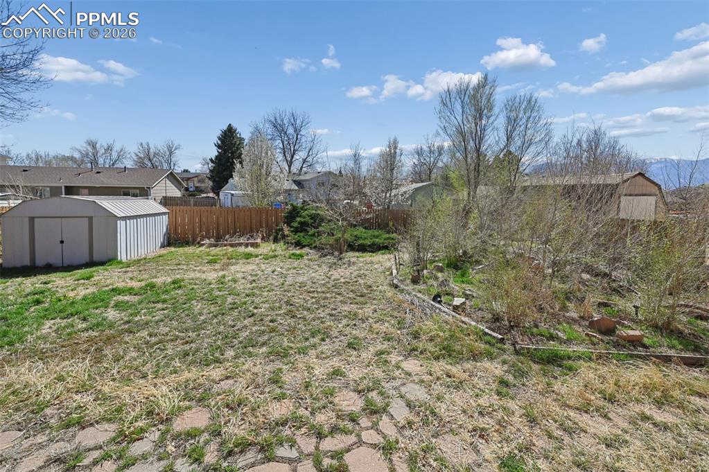 4963 Ridenour Drive Colorado Springs, CO 80916 - Photo 23 of 25 Fenced yard featuring a shed and a residential view