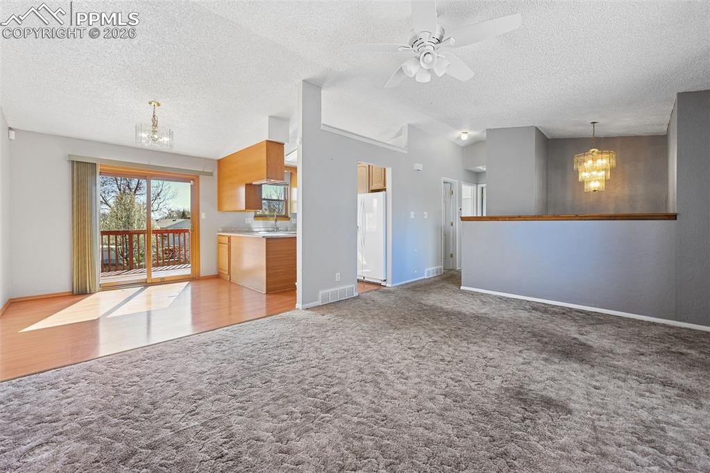 4963 Ridenour Drive Colorado Springs, CO 80916 - Photo 5 of 25 Unfurnished living room with a chandelier, ceiling fan, and light colored carpet