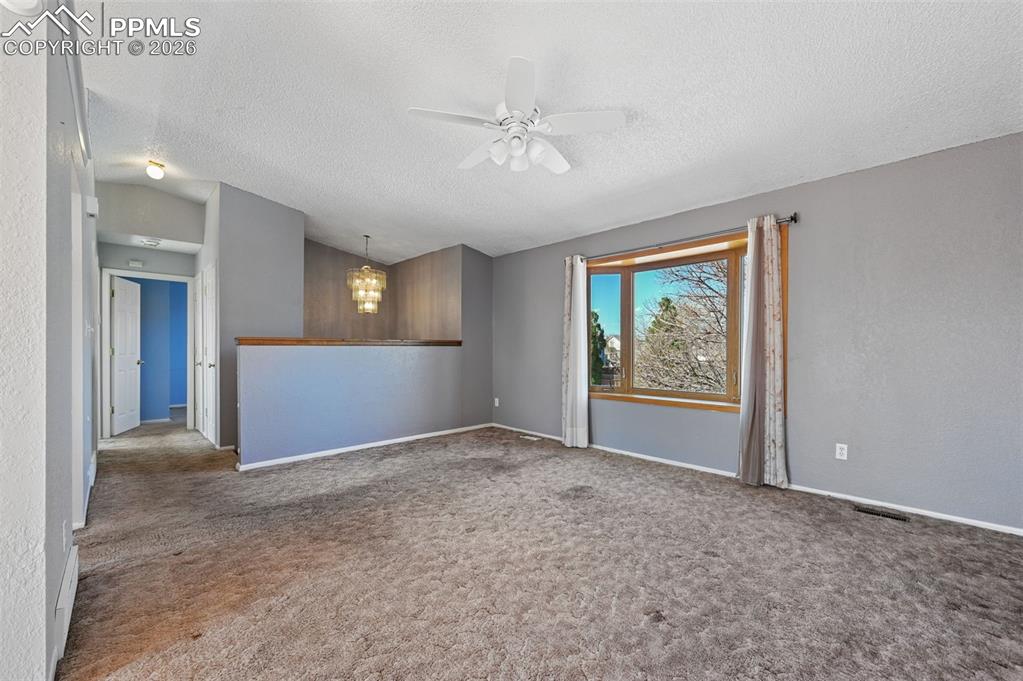 4963 Ridenour Drive Colorado Springs, CO 80916 - Photo 6 of 25 Unfurnished room with a ceiling fan, carpet, and suspended lighting