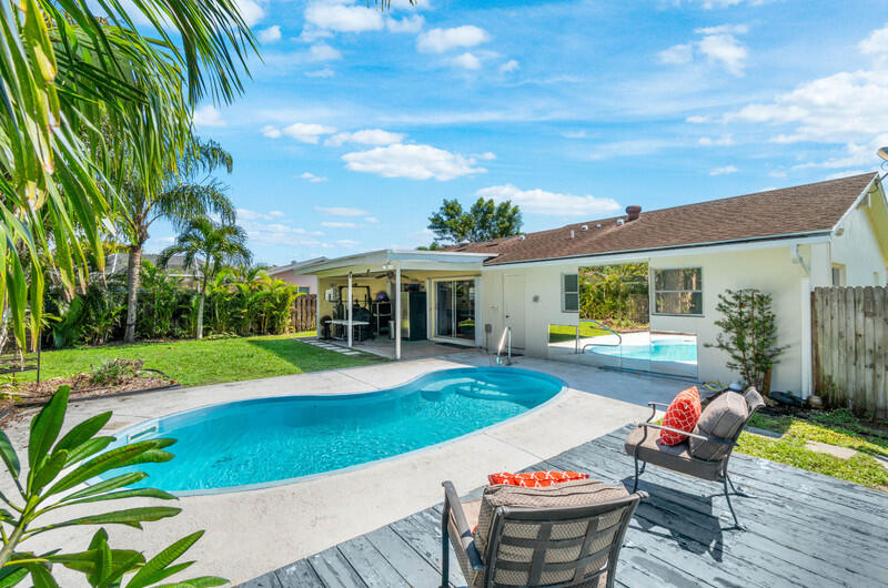 22775 Neptune Road Boca Raton, FL 33428 - Photo 16 of 18 a view of a patio with couches table and chairs under an umbrella