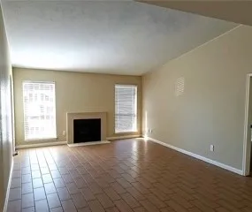 an empty room with windows & a fireplace