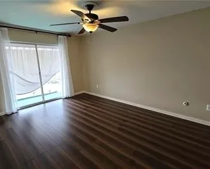 an empty room with wooden floor fan and windows