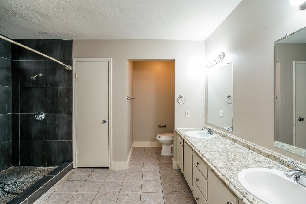 20117 Dawn Mist Drive Humble, TX 77346 - Photo 12 of 16 a bathroom with a granite countertop double vanity sink a mirror and a shower
