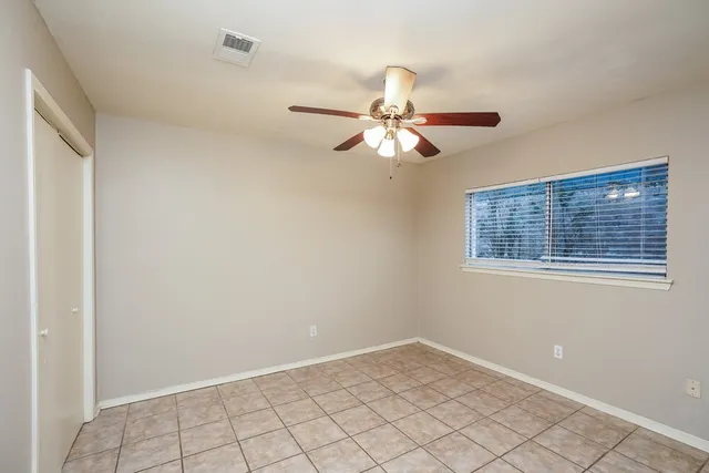 an empty room with a window and a fan