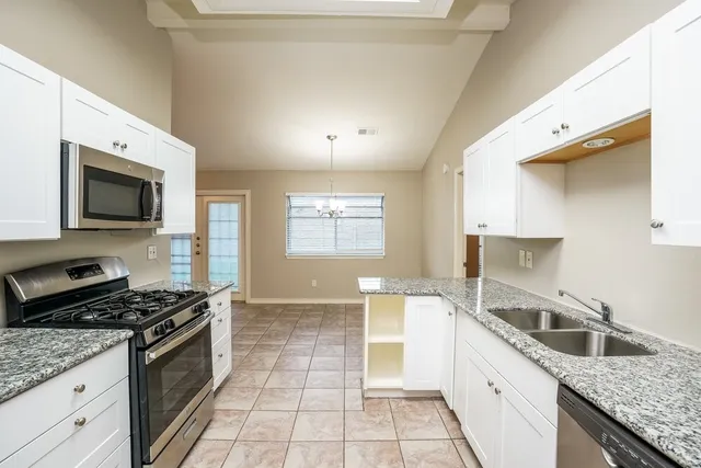 a kitchen with stainless steel appliances granite countertop a stove top oven a sink dishwasher and a refrigerator