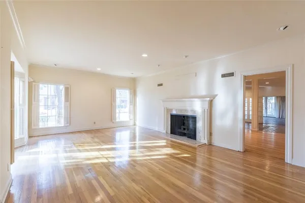 a view of an empty room with wooden floor fireplace and a window