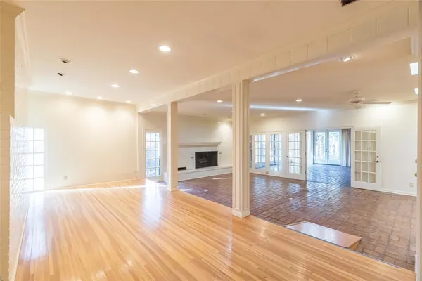 a view of an empty room with wooden floor and a kitchen
