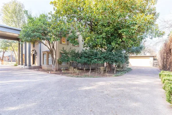 a backyard of a house with table and chairs and a large tree