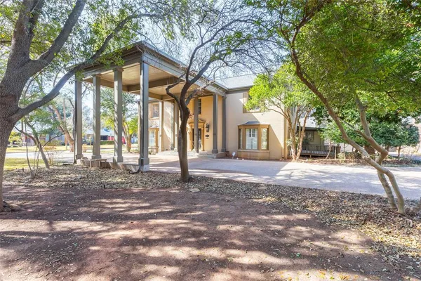 a backyard of a house with large trees and a small barn