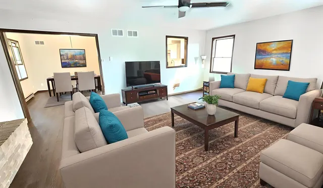 a kitchen with stainless steel appliances granite countertop a refrigerator a sink dishwasher a stove and white countertops with wooden floor