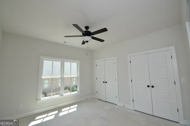 an empty room with windows and ceiling fan