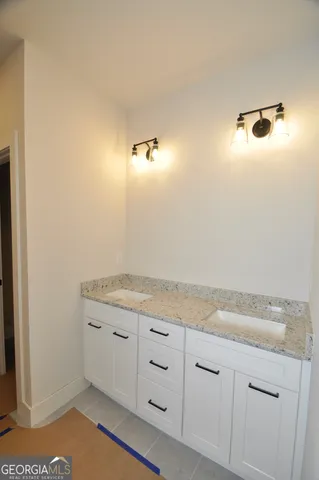 a bathroom with a granite countertop sink and white cabinets