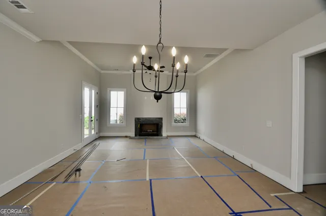 a view of an empty room with chandelier and fire place