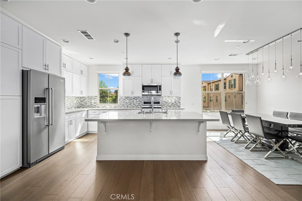 a kitchen with stainless steel appliances a refrigerator a stove a sink dishwasher and white cabinets with wooden floor