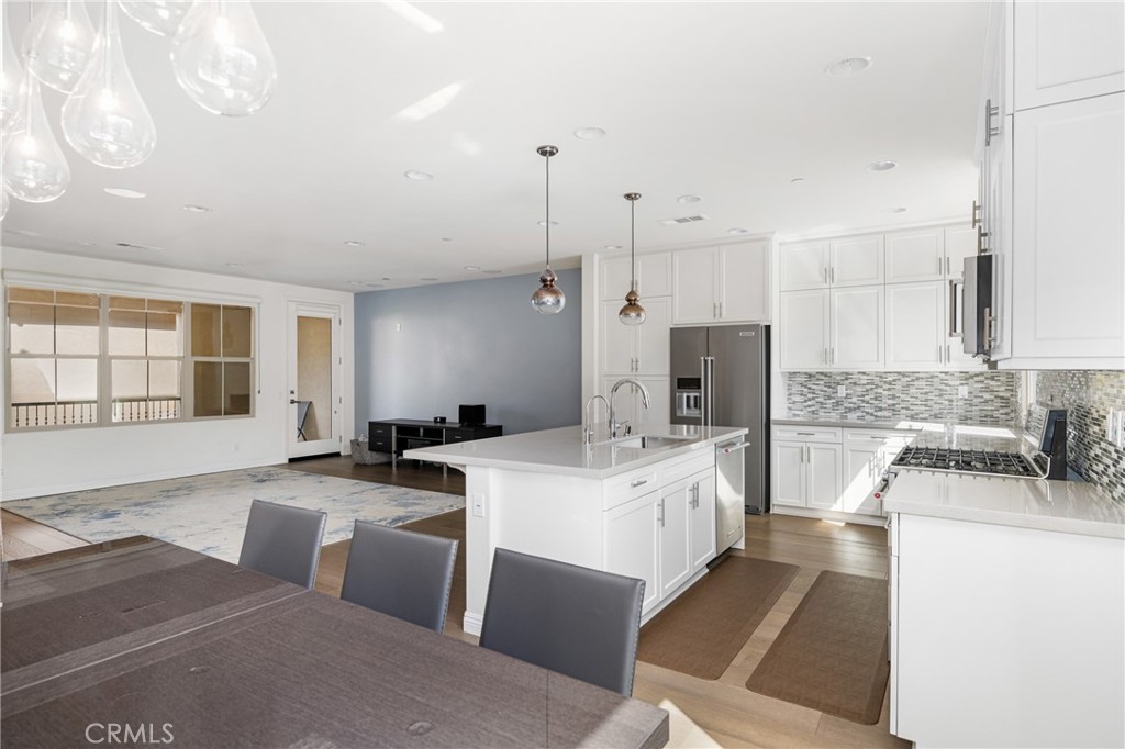 94 Capricorn Irvine, CA 92618 - Photo 13 of 47 a large white kitchen with a stove a sink dishwasher and a refrigerator with wooden floor
