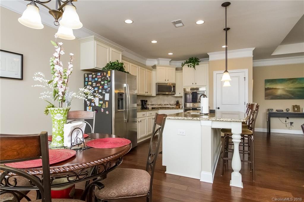 1841 Larkspur Way Tega Cay, SC 29708 - Photo 11 of 27 a kitchen with stainless steel appliances kitchen island granite countertop a dining table chairs and refrigerator
