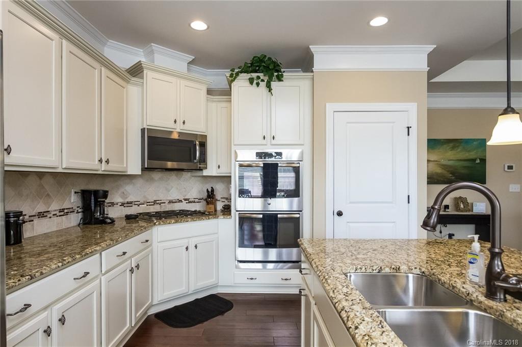 1841 Larkspur Way Tega Cay, SC 29708 - Photo 14 of 27 a kitchen with granite countertop a refrigerator a stove a sink and white cabinets with wooden floor