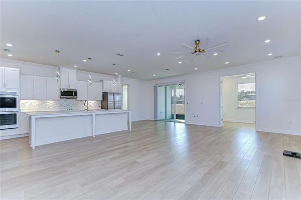 a view of kitchen with kitchen island stainless steel appliances sink cabinets and wooden floor