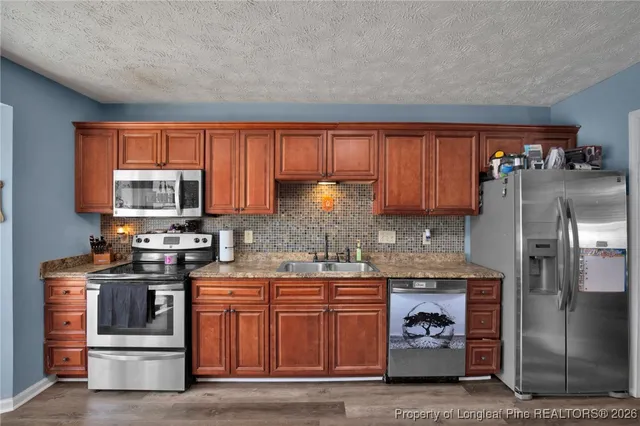 a kitchen with stainless steel appliances granite countertop a stove a sink and a refrigerator
