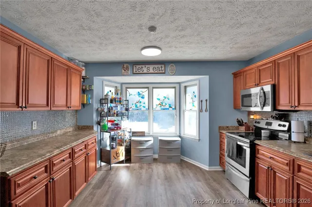 a kitchen with stainless steel appliances granite countertop lots of counter top space and wooden floors