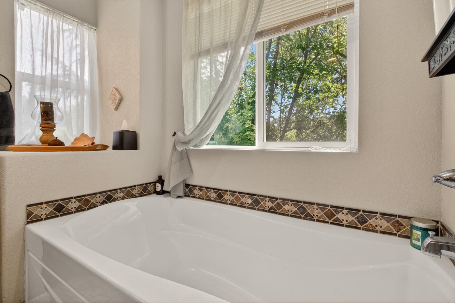 6332 Horseshoe Bar Road Loomis, CA 95650 - Photo 43 of 85 Alcove bathtub with decorative tile border, featuring a window with natural light and a built-in ledge