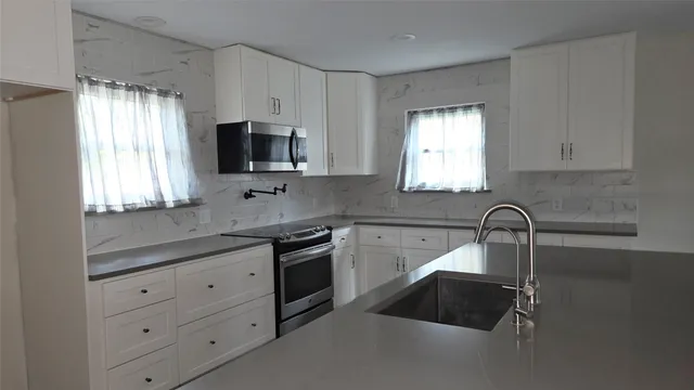a kitchen with granite countertop a sink white cabinets and window