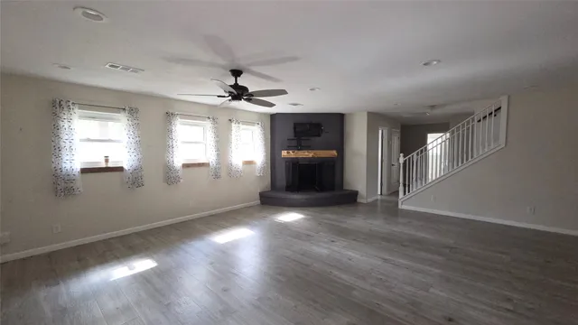 a view of an empty room with window and wooden floor