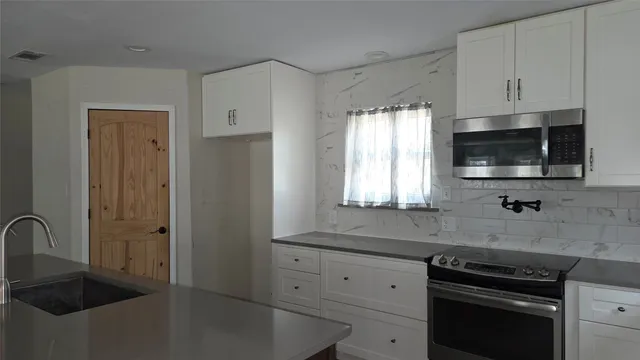 a kitchen with granite countertop a sink stainless steel appliances and cabinets